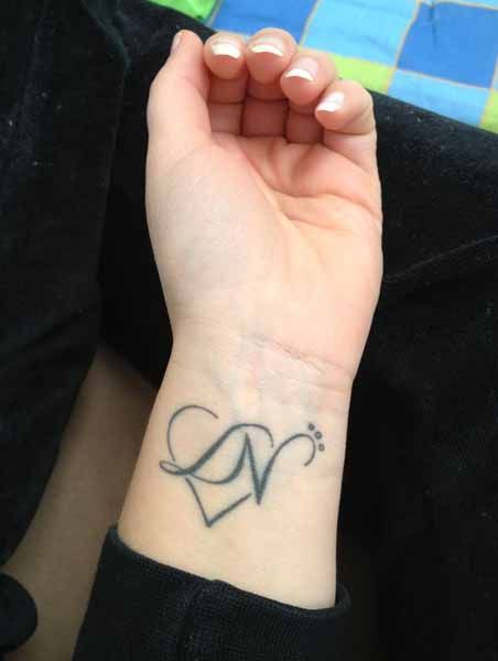 a woman's wrist with a heart tattoo on it