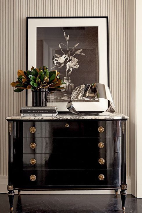 a black and white dresser with flowers on top