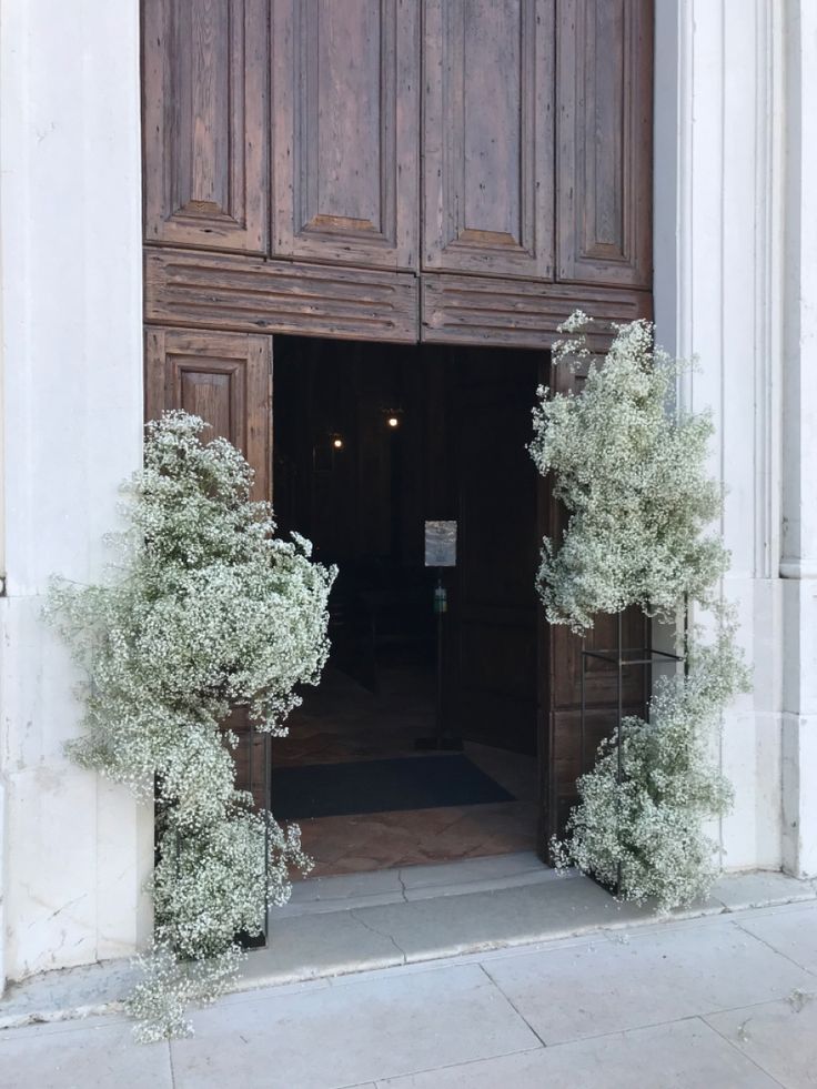 an entrance to a building with wooden doors and plants growing out of the doorways