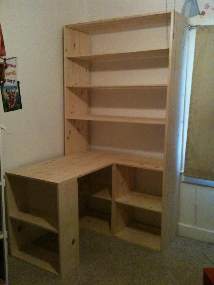 a wooden desk and shelf in the corner of a room with carpeted flooring