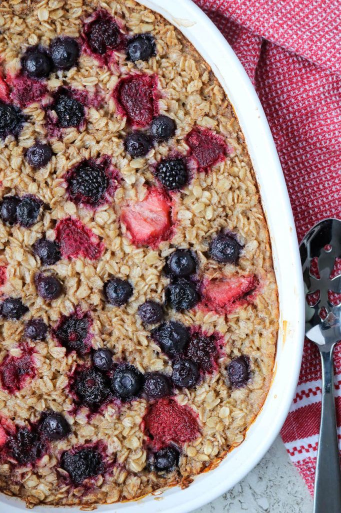 a bowl of oatmeal with berries and blueberries in it next to a spoon