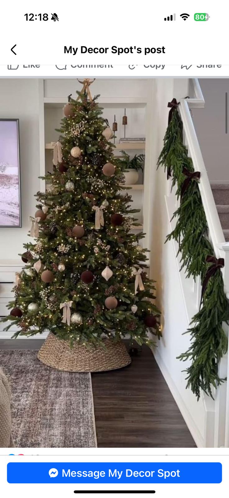 a decorated christmas tree sitting in the corner of a living room next to a stair case