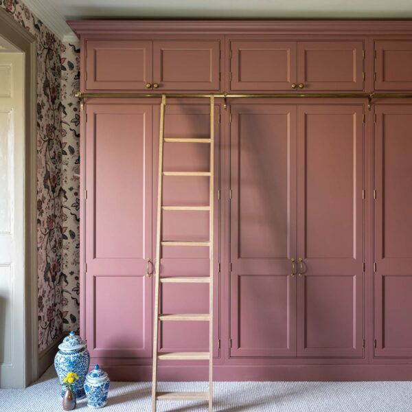 a ladder leaning against a wall in a room with pink walls and floral wallpaper