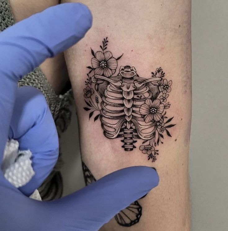 a woman's arm with a tattoo on it and flowers in the background,