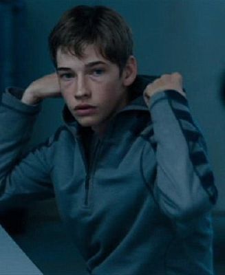 a young man sitting at a desk with his hand on his head