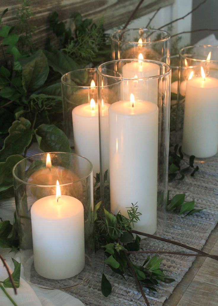 candles are lit on a table surrounded by greenery