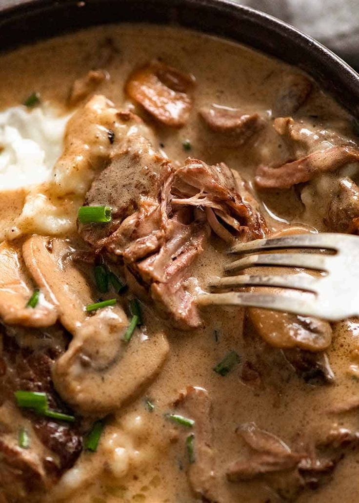 a close up of a plate of food with meat and mushrooms on top, mashed potatoes