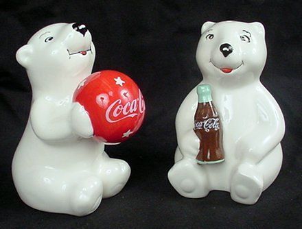 two white polar bears holding coca - cola bottles and a red ball on a black background