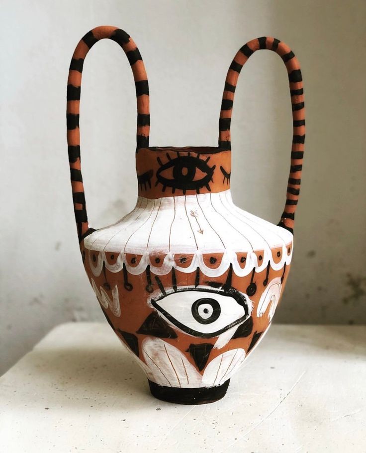 a vase with an eye on it sitting on a table