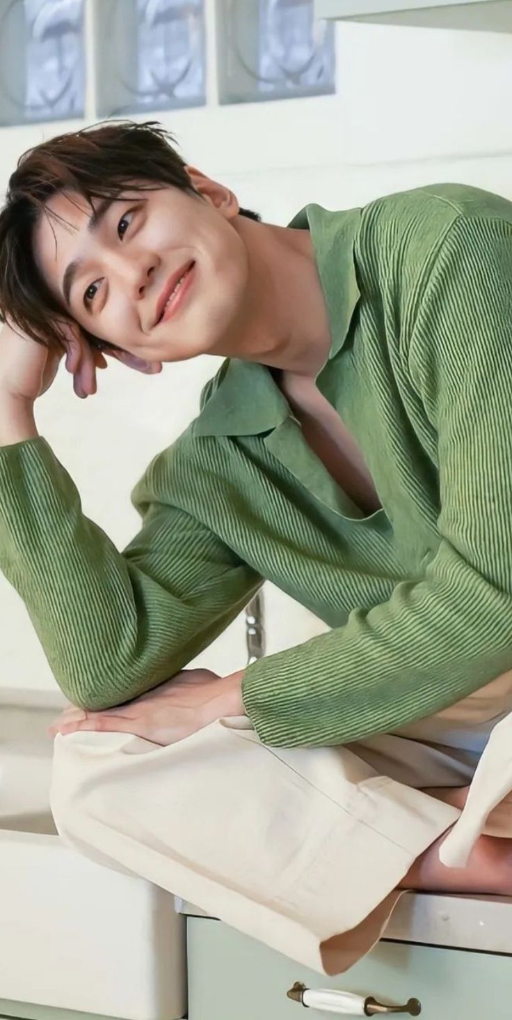 a man sitting on top of a kitchen counter next to a white oven and sink