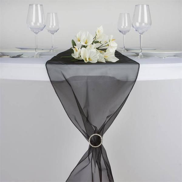 the table is set with white flowers and wine glasses on it, along with a black organ - net runner