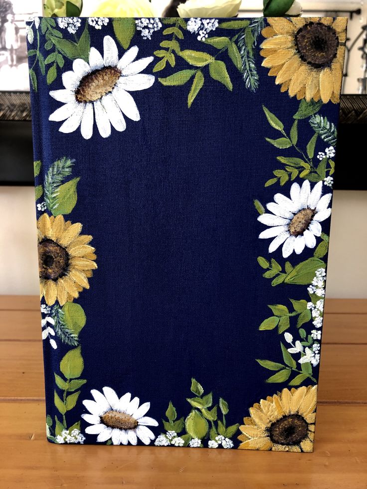 a blue bag with sunflowers and leaves on the front is sitting on a wooden table