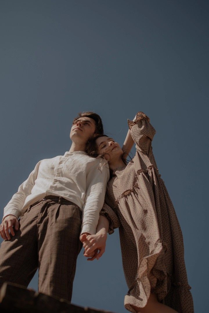 a man and woman standing on top of a building with their arms around each other