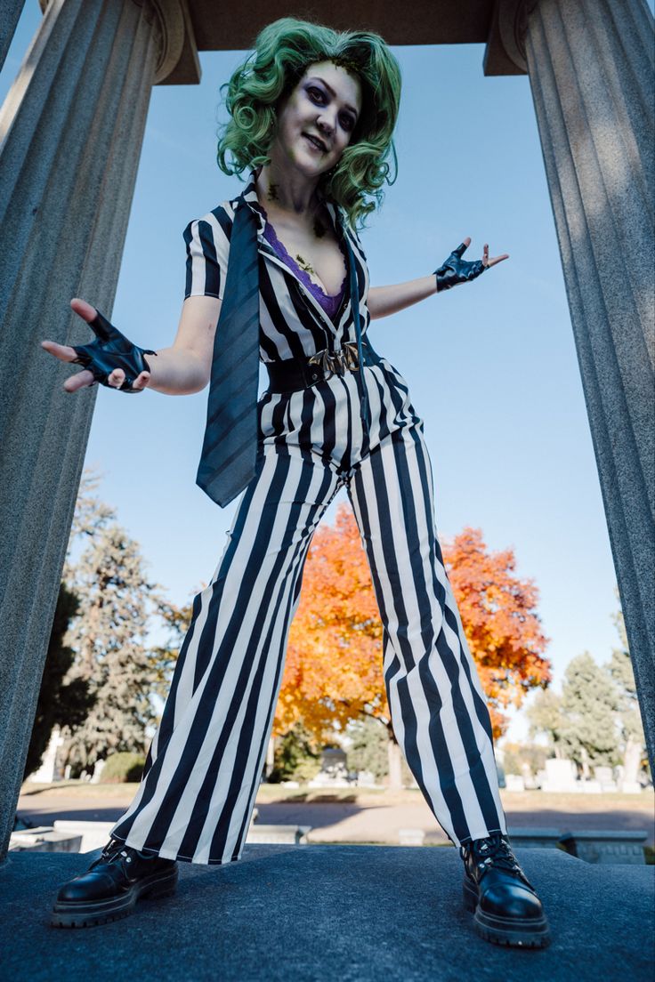 a woman dressed as beetle costume posing in front of a column with her hands out