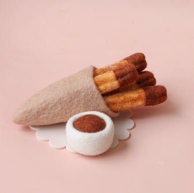 there is a small felt cone with cinnamon sticks sticking out of it and a white bowl on the side