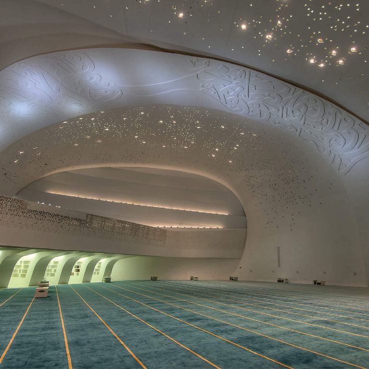 an indoor swimming pool in a large building with blue carpet and lights on the ceiling