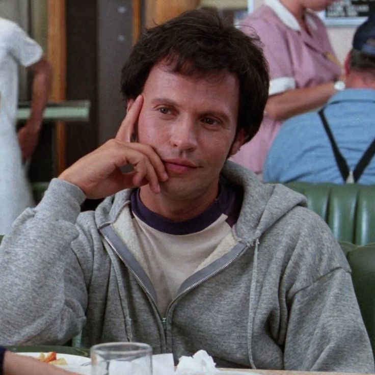 a man sitting at a table with food in front of him and people behind him