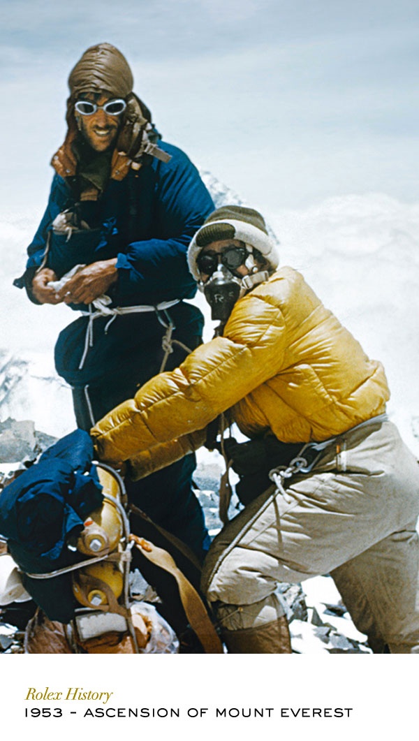 two people sitting on top of a mountain next to each other with skis and snowboards