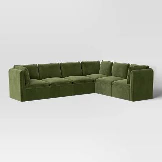 a large green sectional couch sitting on top of a white floor