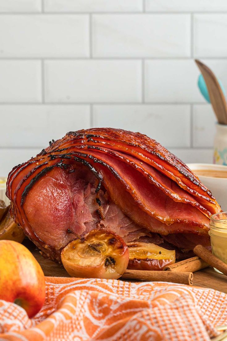 there is a large piece of meat on the table next to some fruit and bread