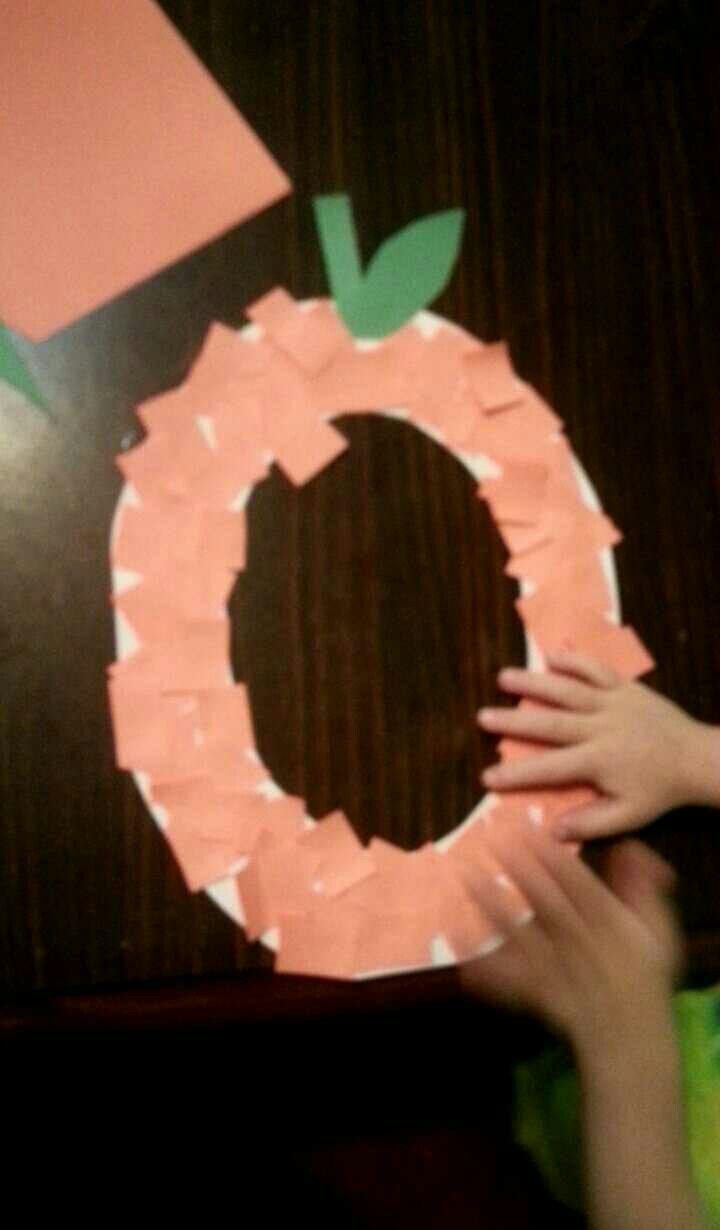 someone is making a paper wreath with the letter o on it and holding their hands