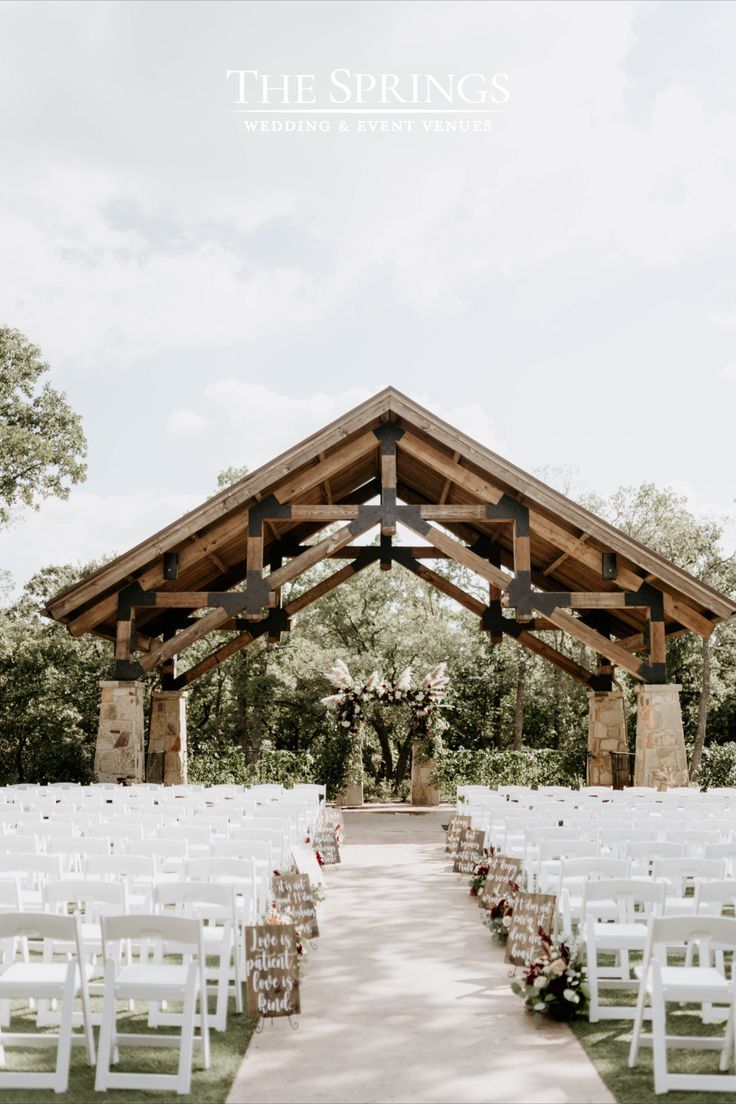 an outdoor ceremony setup with white chairs and floral centerpieces at the springs wedding venue