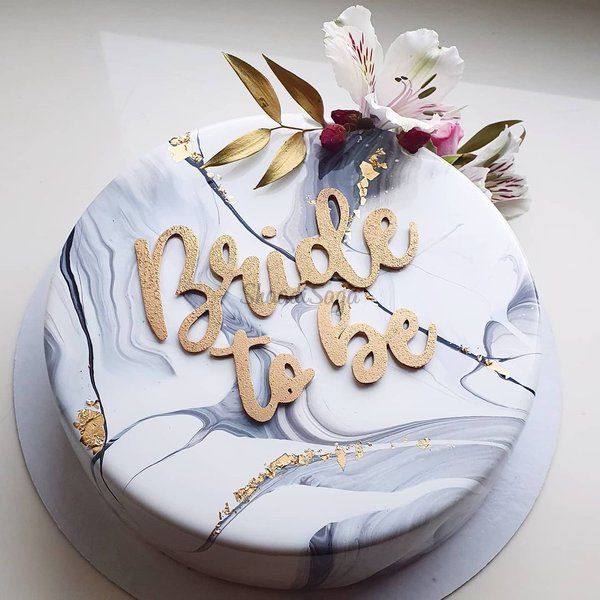 a white cake with gold lettering and flowers on top