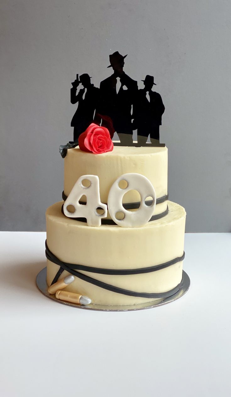 a three tiered cake decorated with silhouettes and the word 40 on top, sitting on a table