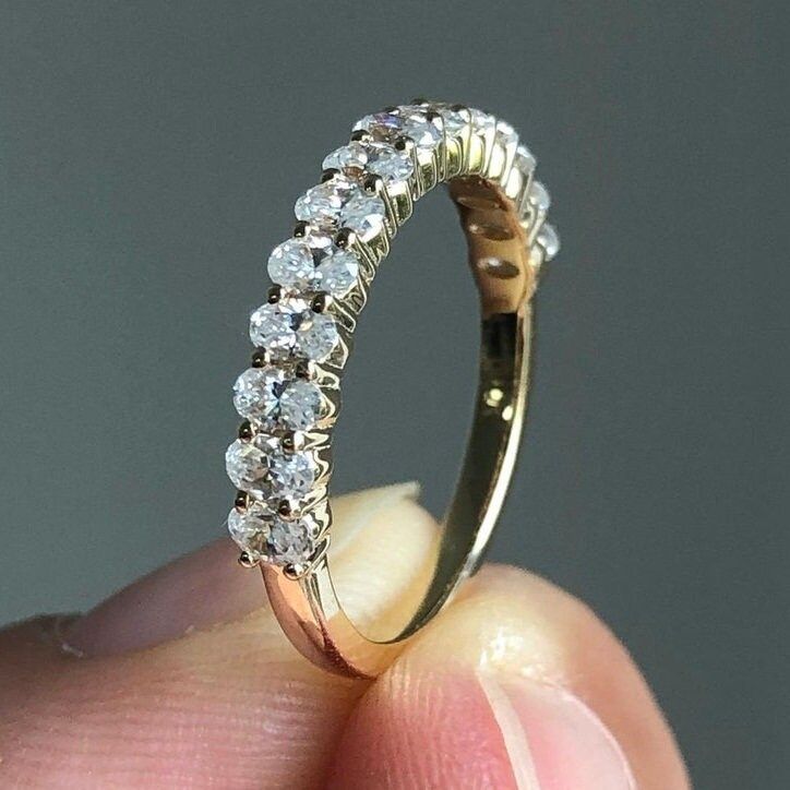 a close up of a person's hand holding a ring with diamonds on it