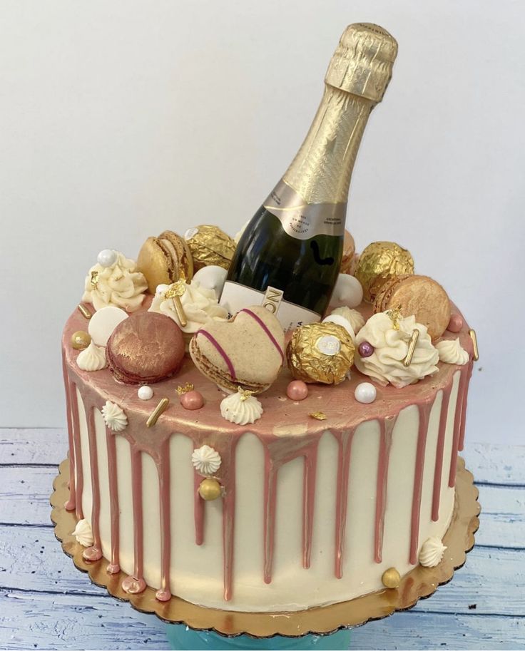 a decorated cake with a bottle of champagne and chocolate candies on the top layer