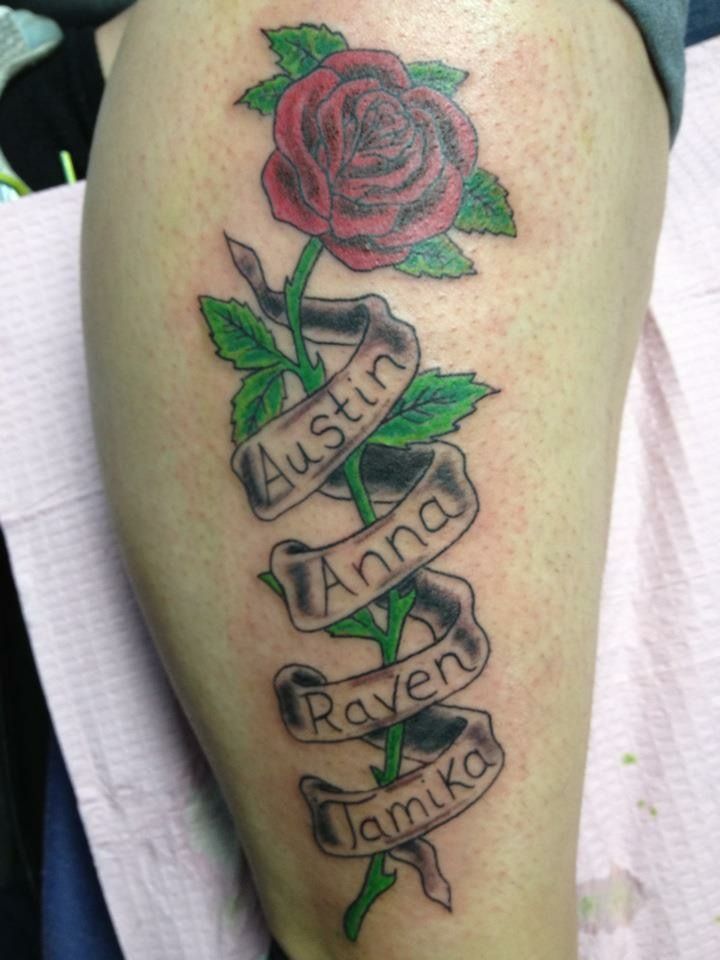 a rose with ribbon and name tattoo on the thigh for women's leg tattoos