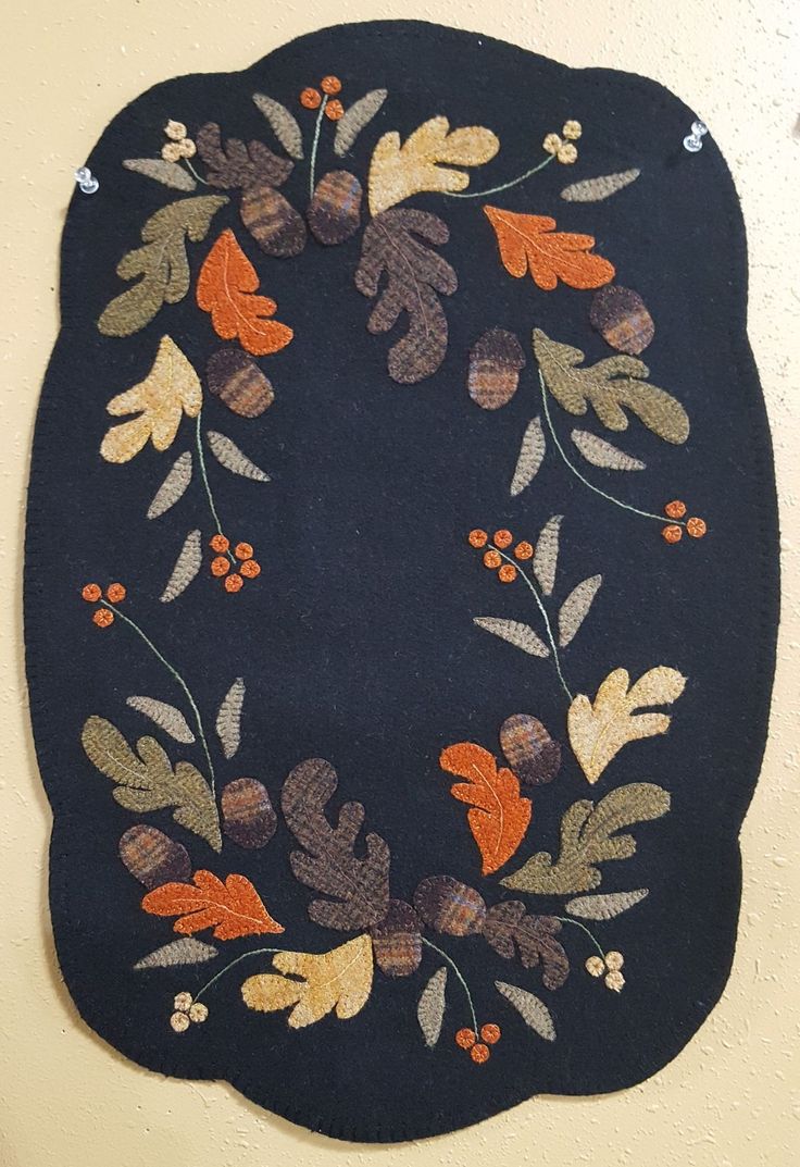 a black rug with leaves and berries is hanging on the wall next to a door