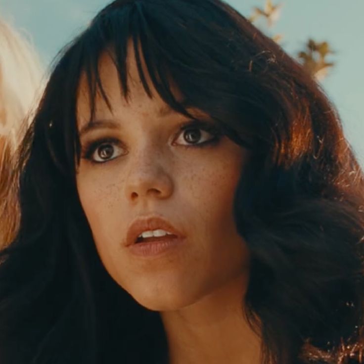 a close up of a woman with long hair and blue eyes looking at the camera