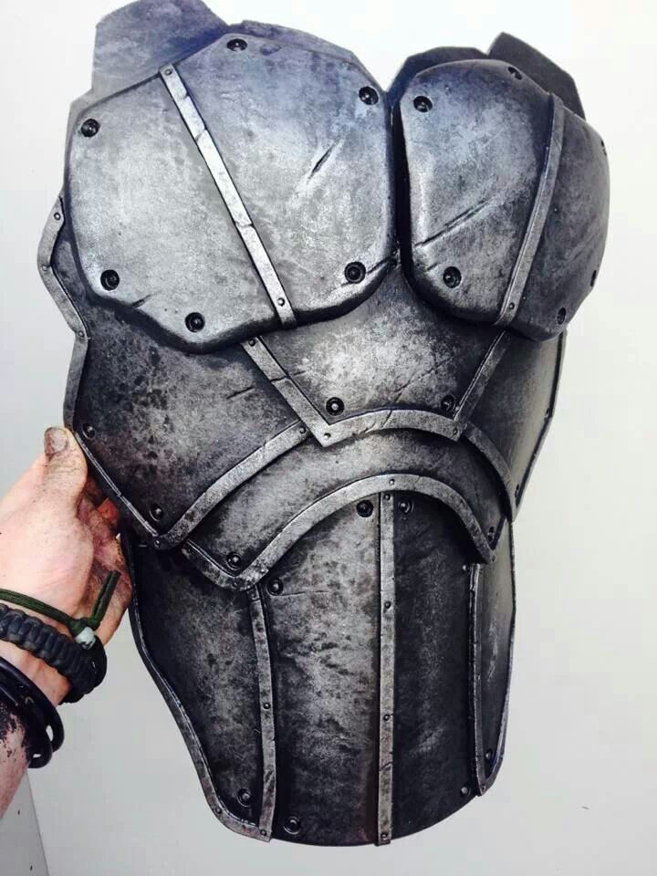 a person is holding up a large metal helmet