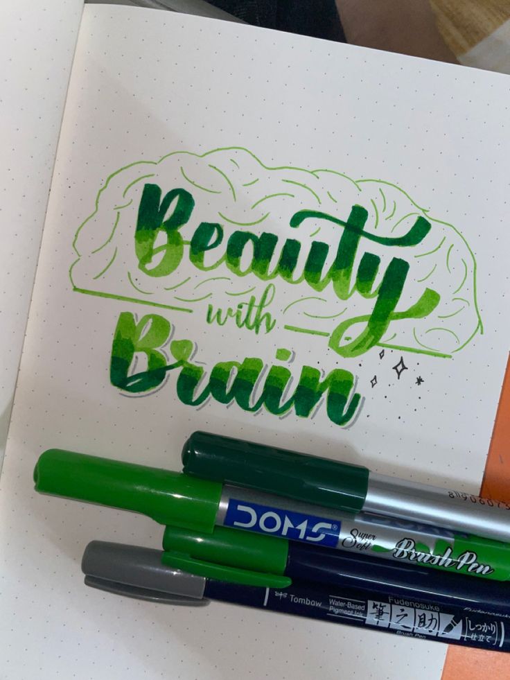 three pens sitting on top of a notebook with the words beauty with brain written in green ink