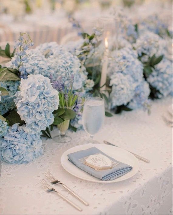 the table is set with blue flowers and silverware