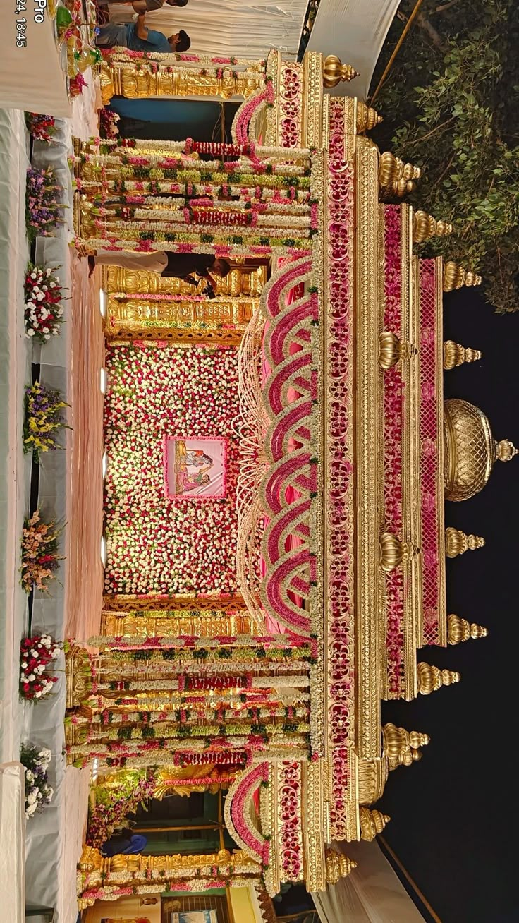 an elaborately decorated building with gold and pink decorations on the outside, in front of a tree