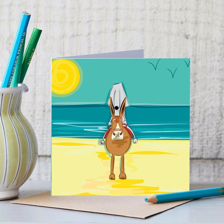 a card with a cartoon horse on the beach next to a cup and pencils