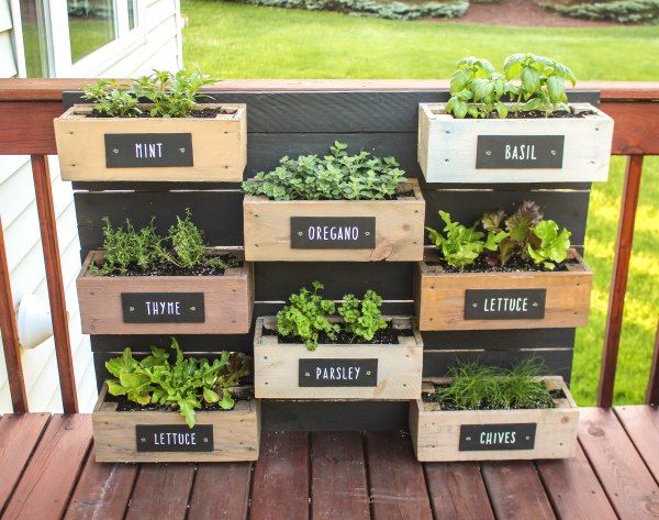 a stack of wooden crates filled with plants on top of a porch next to a house