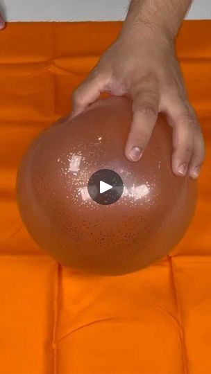 a person holding an inflatable ball on top of an orange sheeted surface