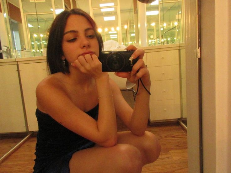 a woman sitting on the floor taking a selfie in front of a mirror with her camera