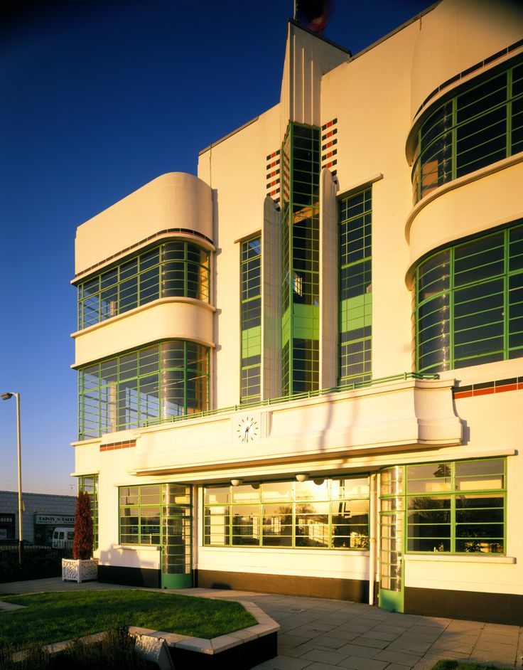 an art deco building with green shutters on the front and side windows at dusk