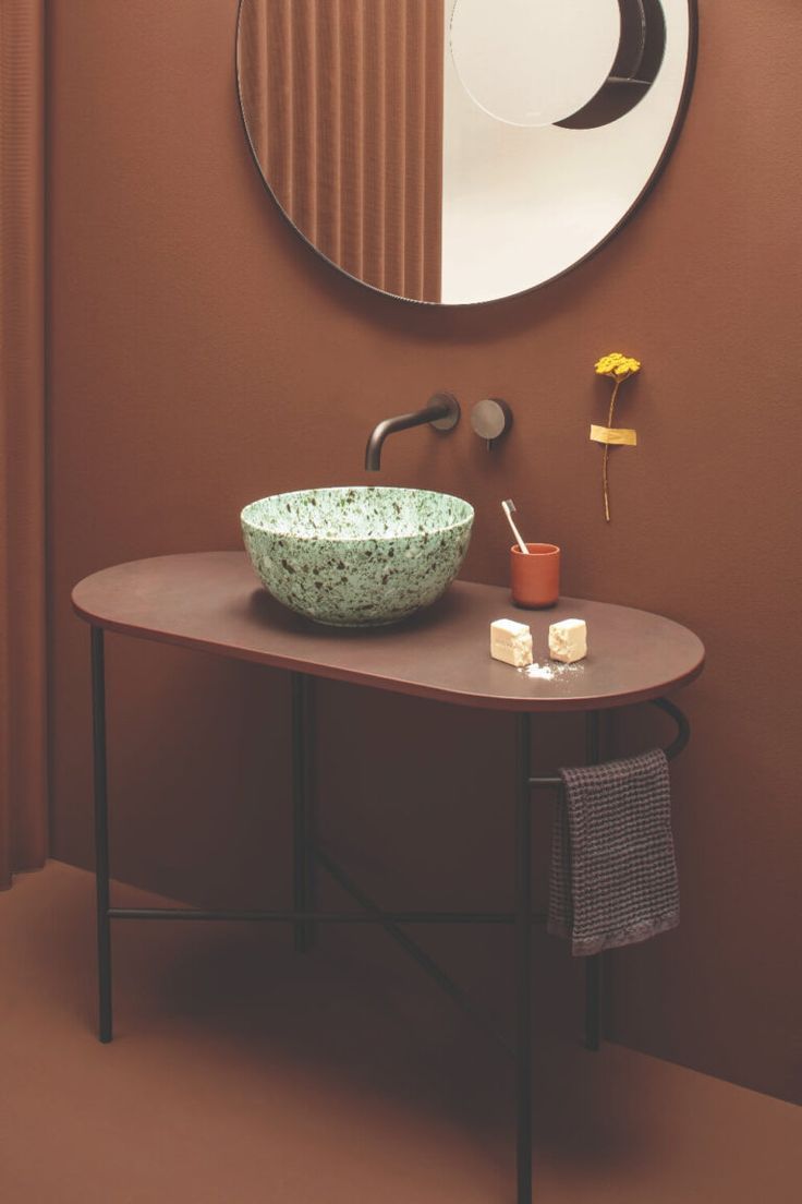 a bowl sink sitting on top of a wooden table next to a mirror above it