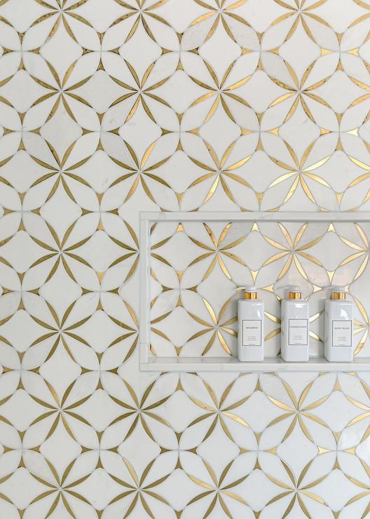 three bottles are sitting on a shelf in front of a wall with gold and white designs