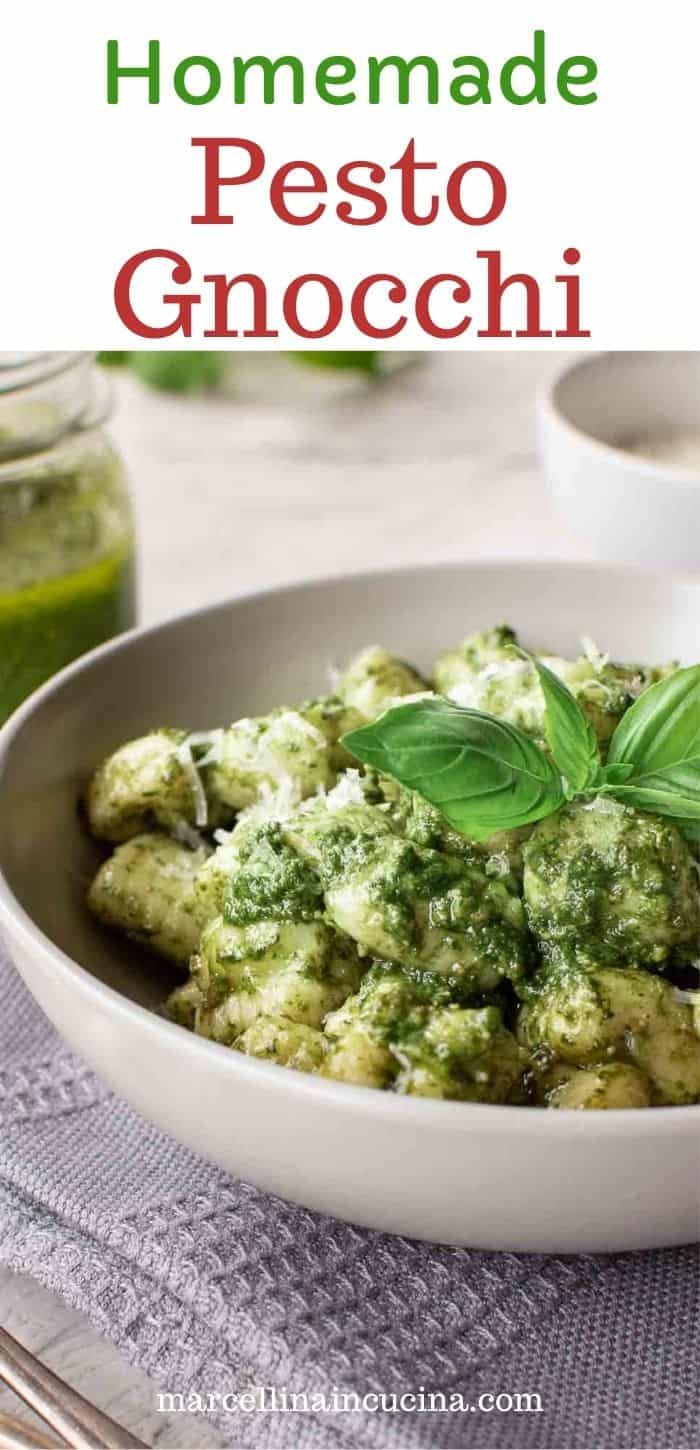 a white bowl filled with pesto gnocchini and topped with fresh basil