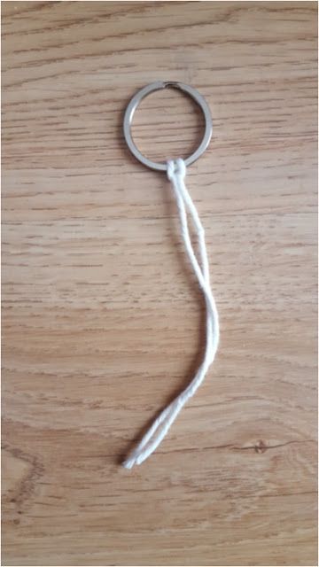 a close up of a key chain on a wooden table with a white string attached to it