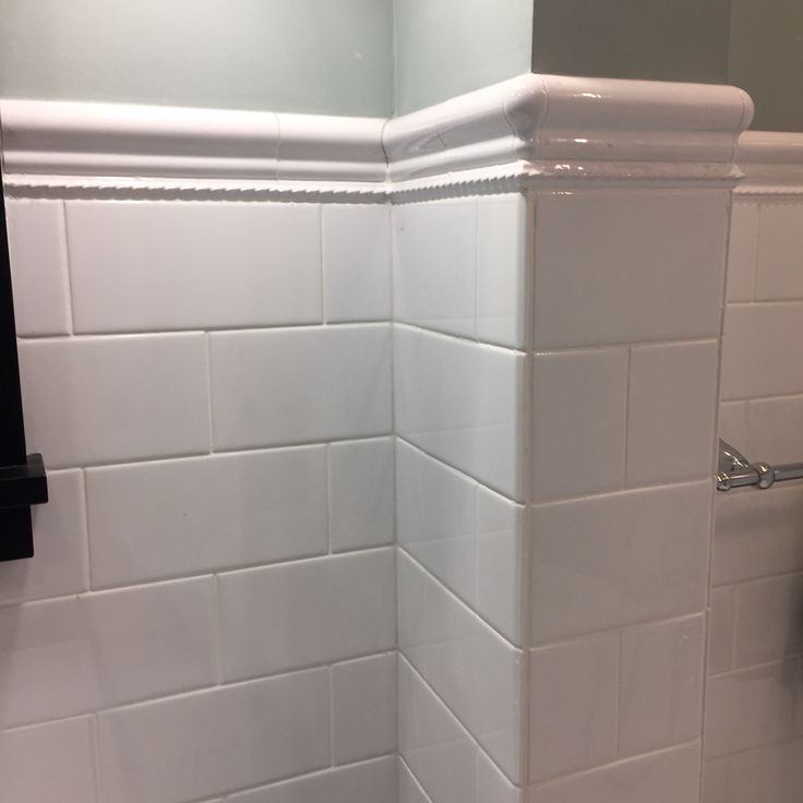 the corner of a bathroom with white tile