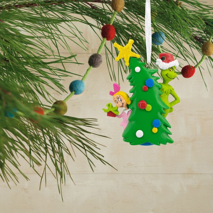 a christmas tree ornament hanging from a pine tree with decorations on it and an elf