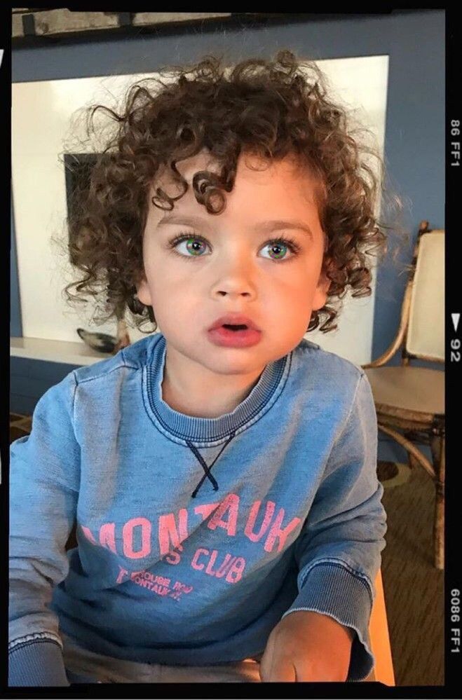 a young child with curly hair sitting at a table