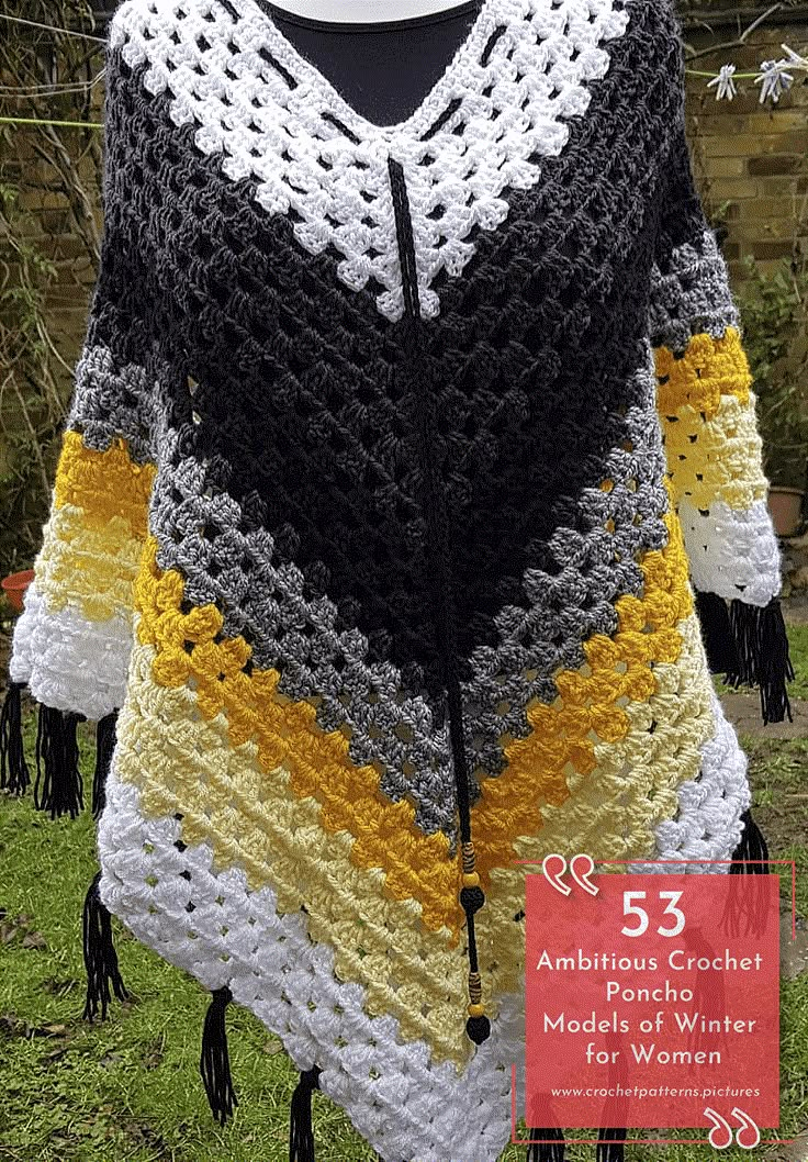 a crocheted poncho on display in front of a brick wall